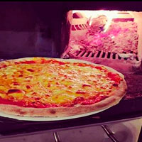 pizza de fina masa con fuego de horno de leña al fondo